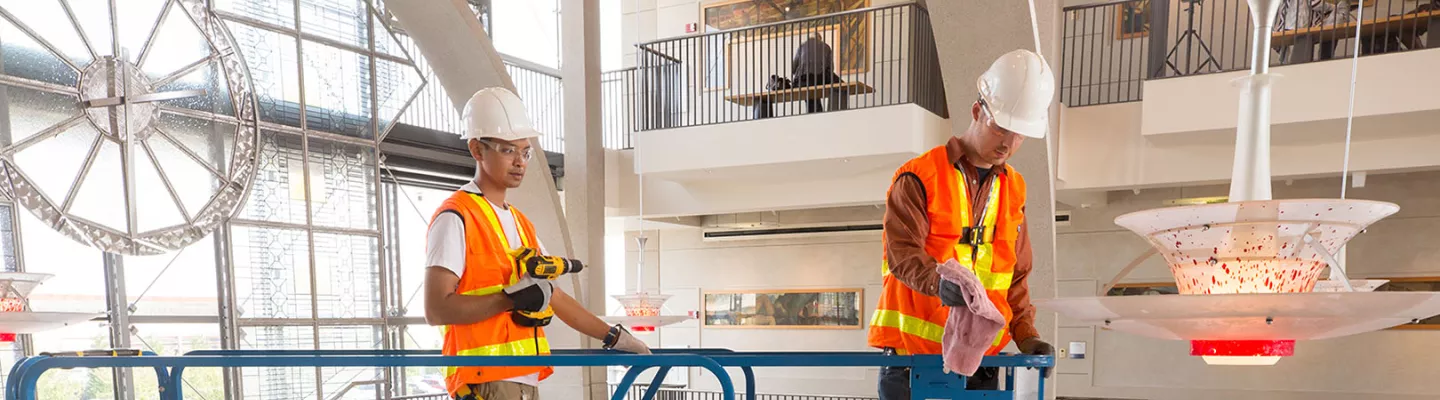 Dos trabajadores en un elevador de tijera dentro de un edificio