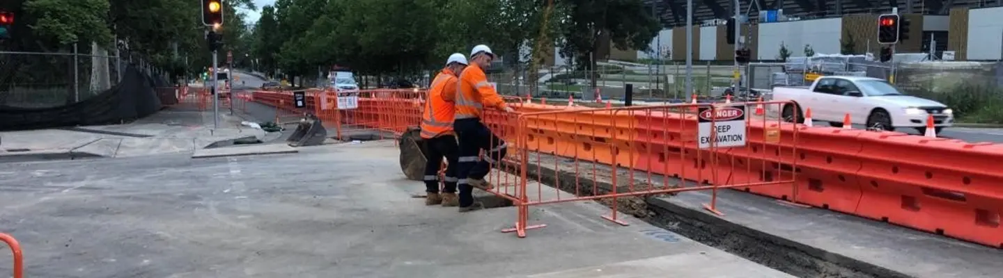 Trabajadores parados frente a barreras de seguridad llenas de agua instaladas a lo largo de una zona de construcción en carretera.