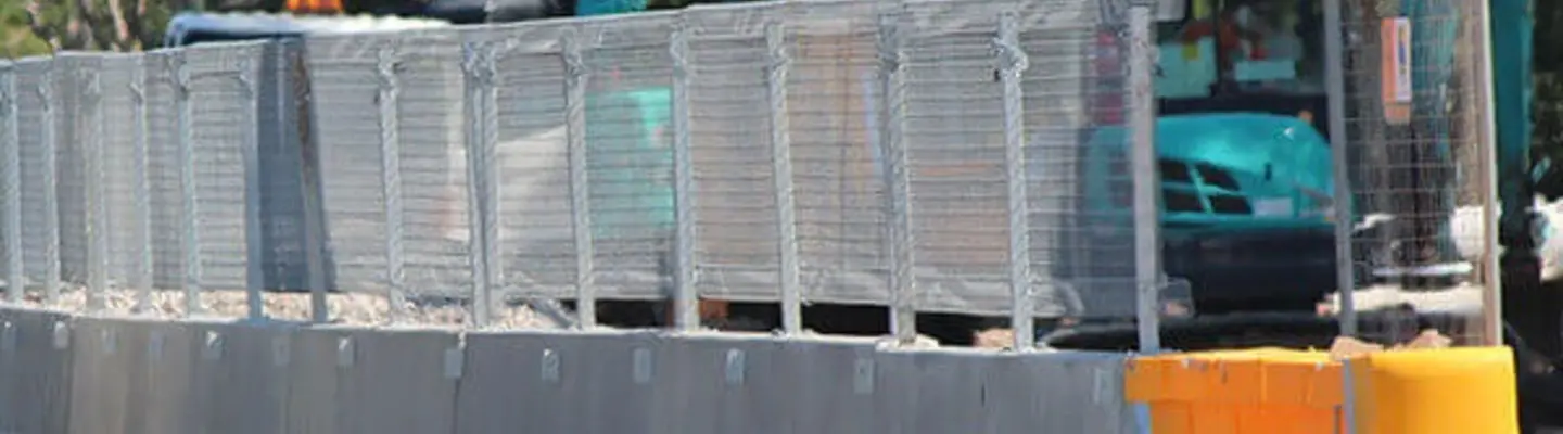 Barreras de seguridad instaladas a lo largo de un área de construcción junto a la carretera para proteger a los trabajadores y guiar el tráfico a través de la zona de trabajo.