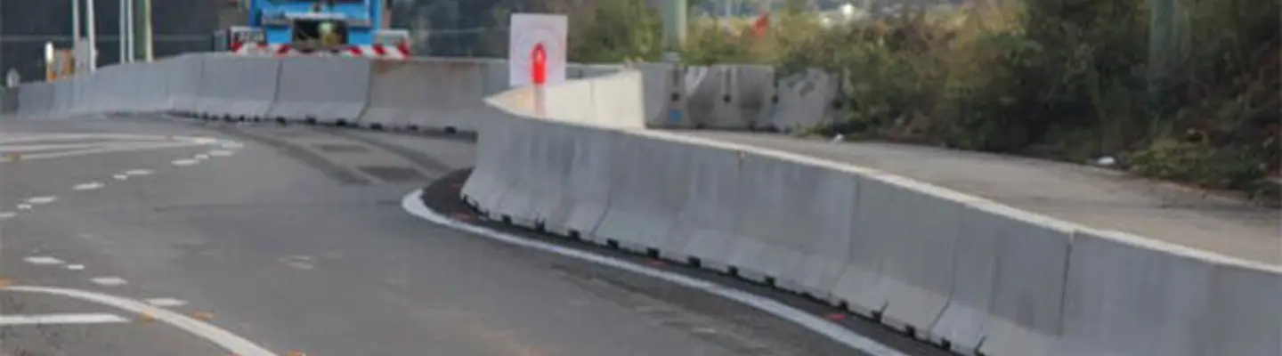 Barreras de seguridad largas que recubren una zona de construcción de calzadas para proteger a los trabajadores y guiar el flujo de tráfico.