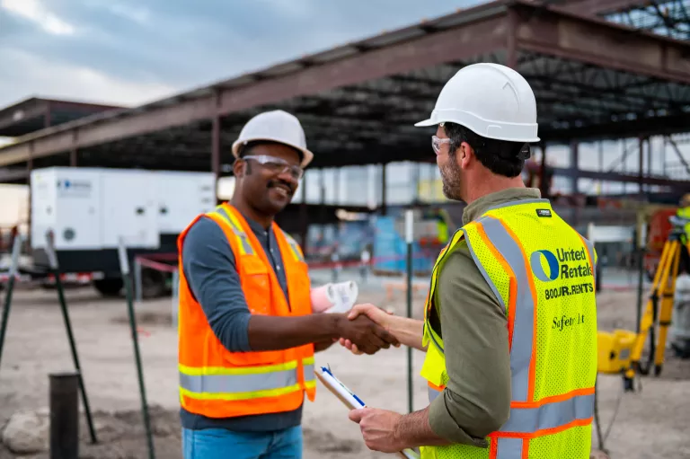 Trabajadores con cascos estrechando las manos