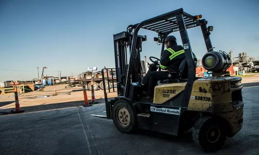 Trabajador que usa un montacargas en el sitio de trabajo