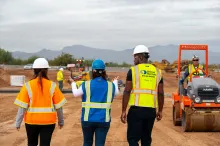 3 personas en el sitio de trabajo caminan en dirección a un equipo