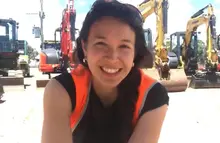 Natasha Haddad in front of excavators at a construction site, highlighting Orange Hire's equipment and team.