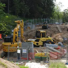 Different types of construction equipment in use at a site, supporting tasks like excavation, lifting, and barrier installation.