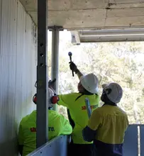 Workers positioning props to provide temporary structural support during an active construction project.