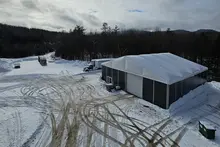 Gran tienda de construcción en un entorno exterior nevado, con su duradera cubierta de vinilo y su diseño climatizado.