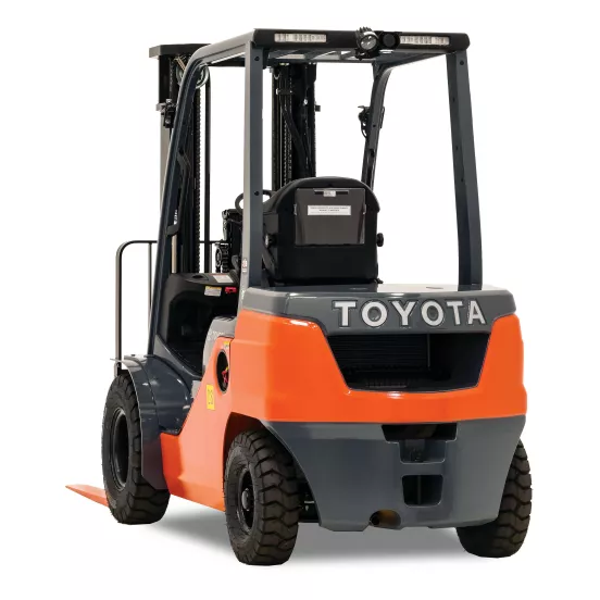 Vista trasera de un montacargas de almacén Toyota naranja y negro con mástil de elevación negro y horquillas naranjas con cabina abierta.